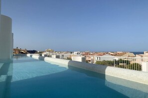 Ein Infinity-Pool auf dem Dach mit freiem Blick auf Stadt und Meer.