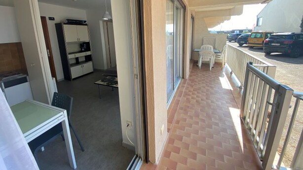 A balcony with a tiled floor, a dining table, and chairs. There is a kitchen area with cabinets and a refrigerator. - Apartment 4 guests near beach with parking (Argelès-sur-Mer)