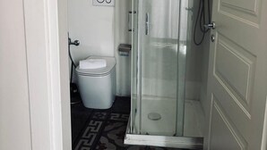 A small bathroom with a shower, toilet, and a patterned floor. - Stanze di Agatha (Catania)