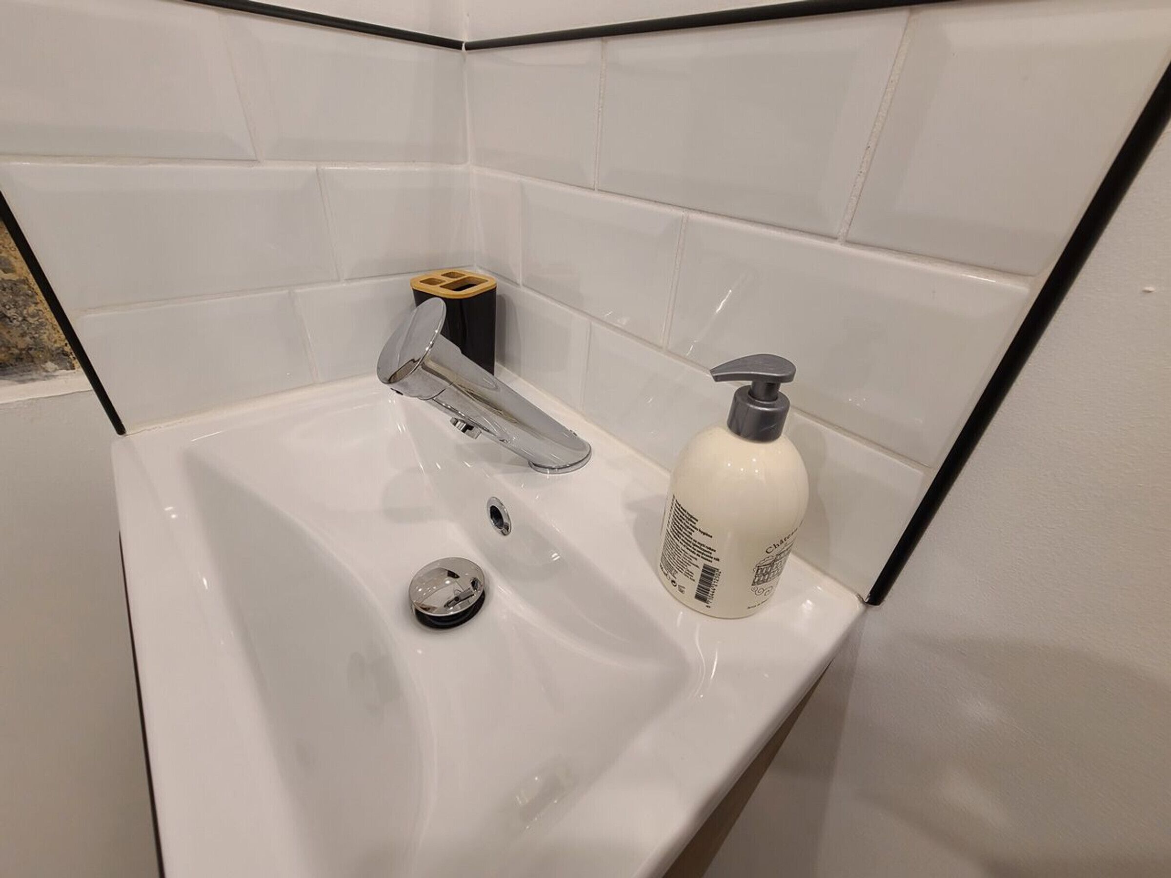 A bathroom with a white sink, a chrome faucet, and a bottle of hand soap.
