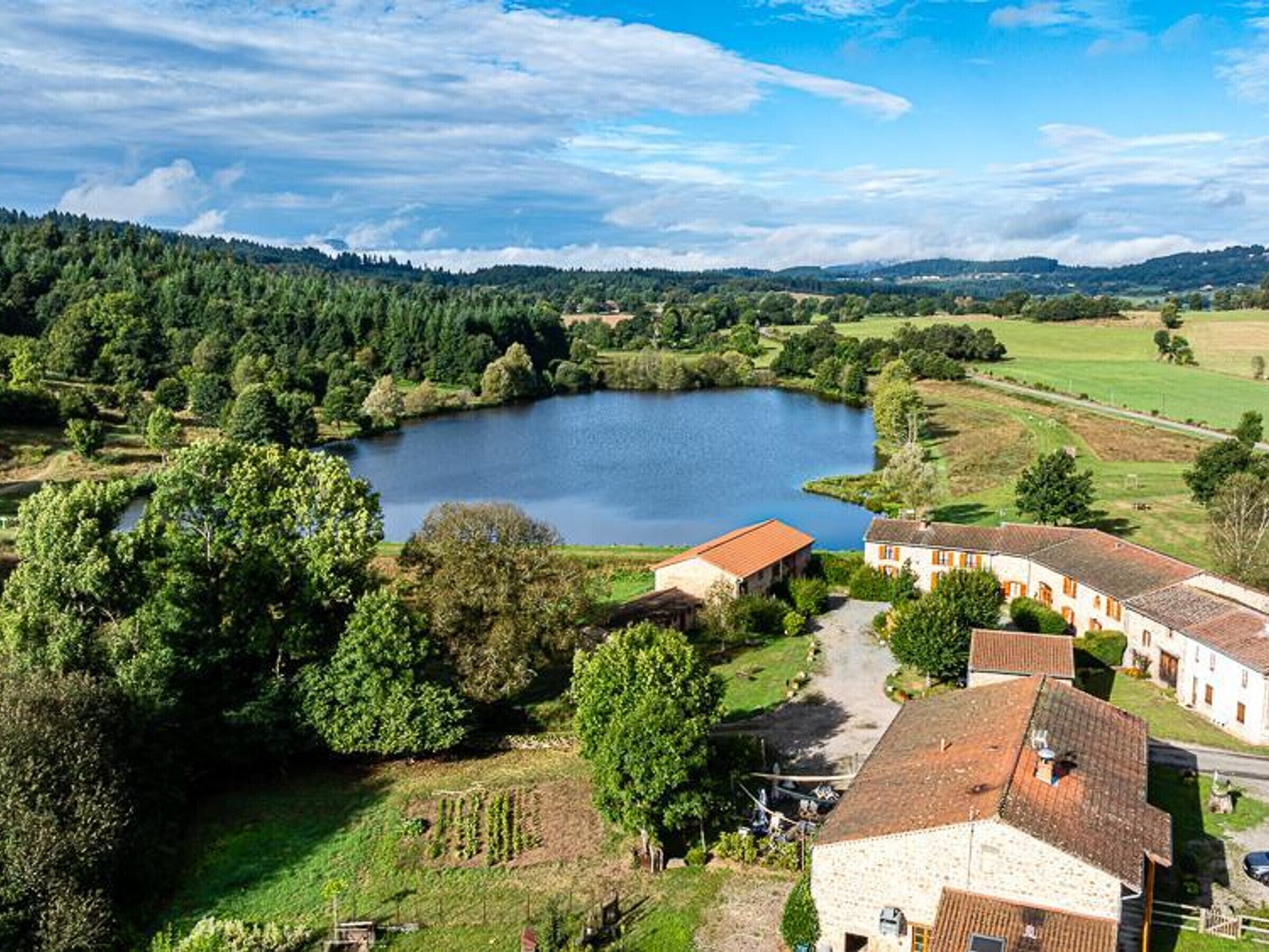 Un paysage rural avec un grand lac, entouré d’une végétation luxuriante et de quelques bâtiments.