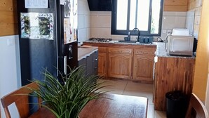 A compact kitchen with wooden cabinets, a refrigerator, a stove, and a toaster.