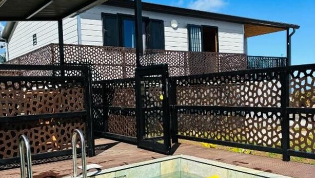 A swimming pool with a metal ladder, a pool float, and a wooden fence.
