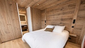 Un dormitorio con cabecera de madera, una cama grande con ropa de cama blanca y suelo de madera.