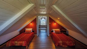 A cozy attic bedroom with two single beds, wooden beams, and a skylight.