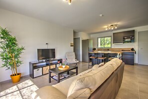 A modern living room with a sofa, a coffee table, a television, and a potted plant.