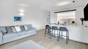 Un soggiorno moderno con un divano grigio, un angolo cottura con un bancone e un'area pranzo con due sedie.