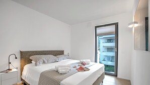 Una moderna camera d'albergo con un letto grande, un comodino, una lampada da lettura e vista sulla città da una grande finestra.