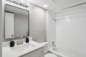 A modern bathroom with a white sink, mirror, and shower.