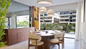Un espace de salle à manger moderne avec une table ronde, des chaises et des luminaires suspendus.