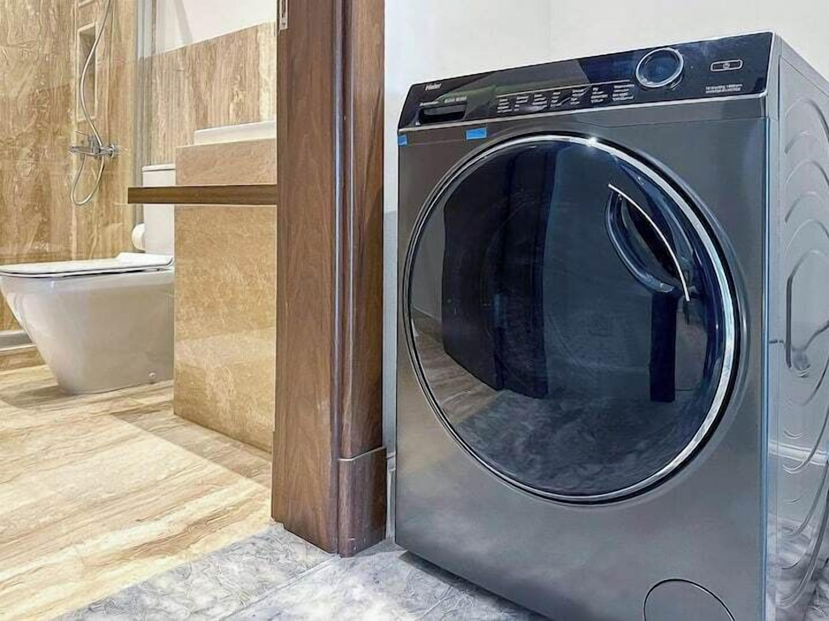 A modern bathroom with a built-in washer and dryer, a toilet, and a shower area.