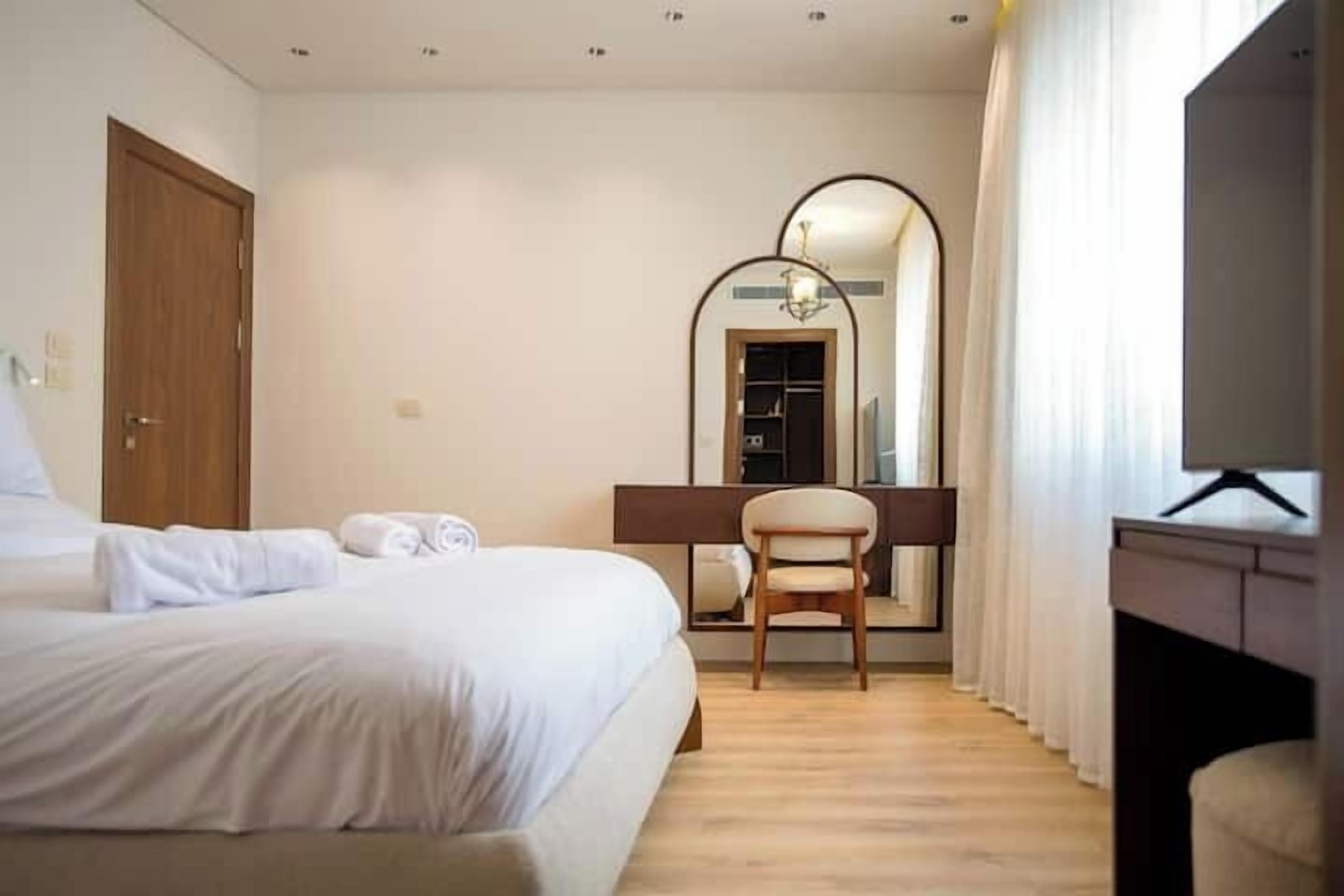 Une chambre d’hôtel avec un lit, une chaise, un bureau et un grand miroir.
