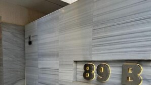 Une entrée moderne, avec une façade en marbre et un escalier menant à une porte portant les numéros « 89 B ».
