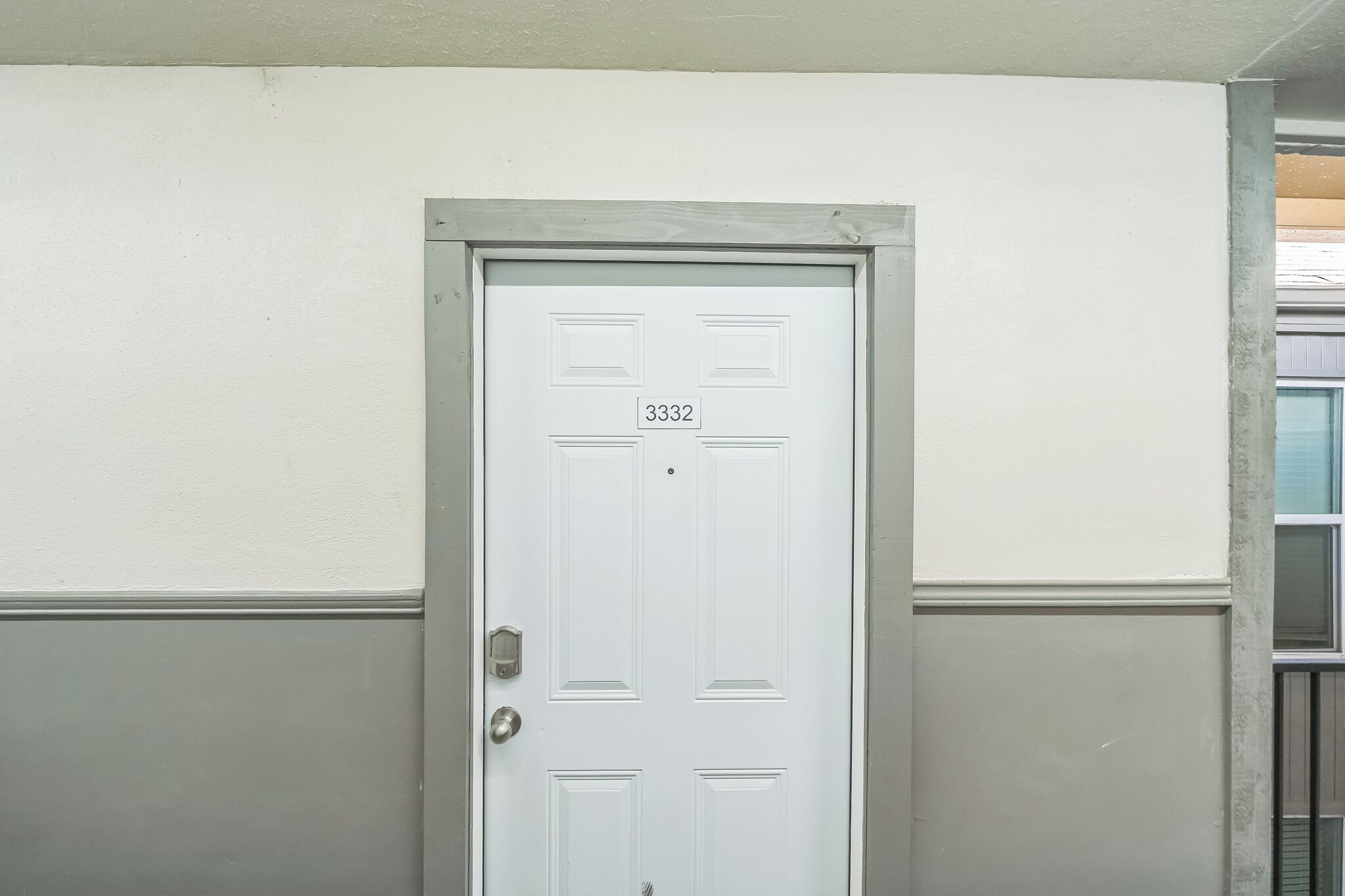 Une porte blanche avec une plaque portant un numéro, une poignée en métal et un judas.