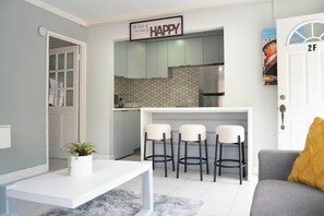Un espace de vie compact comprenant une cuisine, un coin repas avec des tabourets de bar, un canapé et une porte portant le numéro 2F.