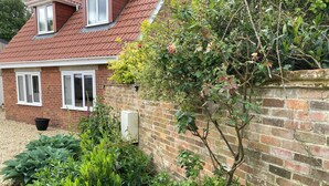 A brick house with a red roof, a brick wall with climbing plants, and a gravel driveway. - Romantic Country Cottage with Private hot tub (Wiltshire)