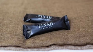 Two TINAH chocolate bars on a brown fabric surface in a hotel room. - Hotel Tinah: Elegance and Comfort Near the Champs-elysees (Paris)