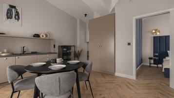 A modern kitchen with a dining area, featuring a round table with chairs, a refrigerator, and a cabinet.