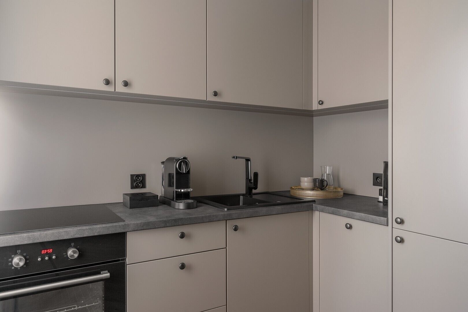 Una cocina moderna con horno empotrado, cafetera y pileta.