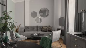 Een moderne woonkamer met een grijze bank, een bijzettafeltje en een televisie. Twee ronde spiegels hangen aan de muur en er staat een plant in de hoek.