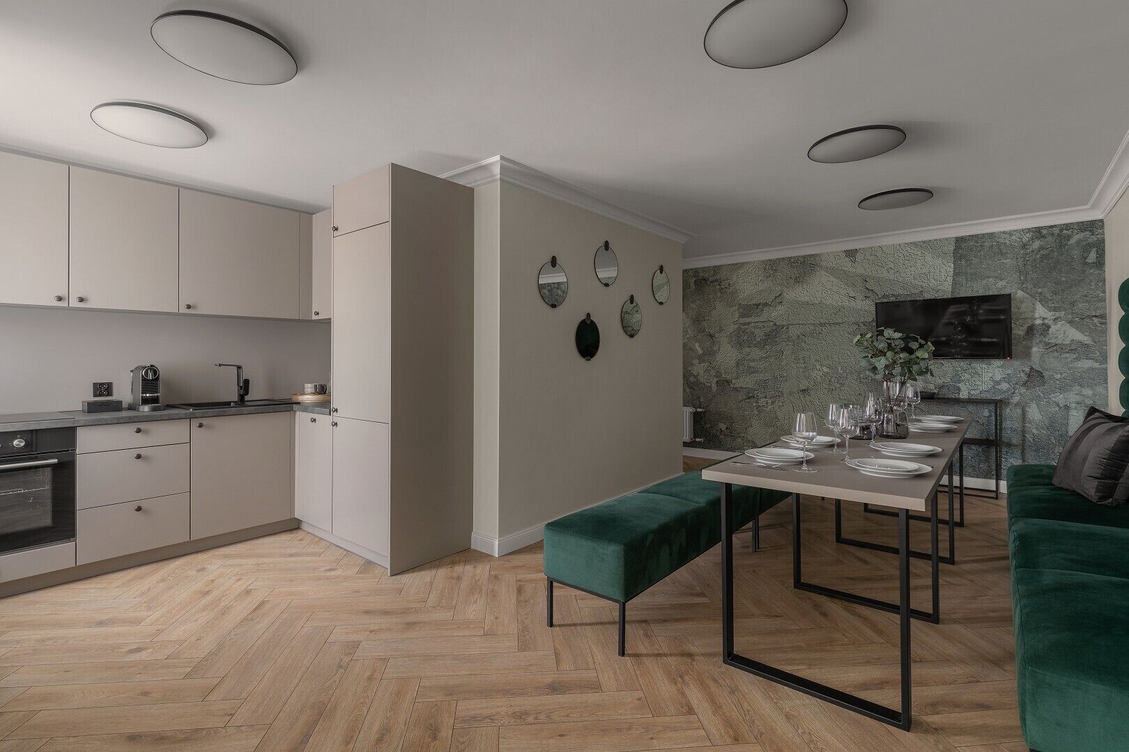 Eine moderne Küche mit integrierten Geräten, ein Essbereich mit einer grünen gepolsterten Bank und einer Wand mit Steinoptik.