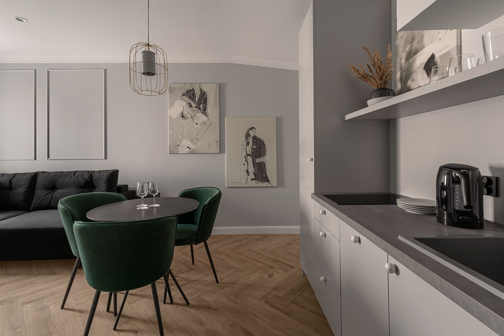 A modern kitchen with a black countertop, a coffee maker, and a dining area with a round table and two chairs.