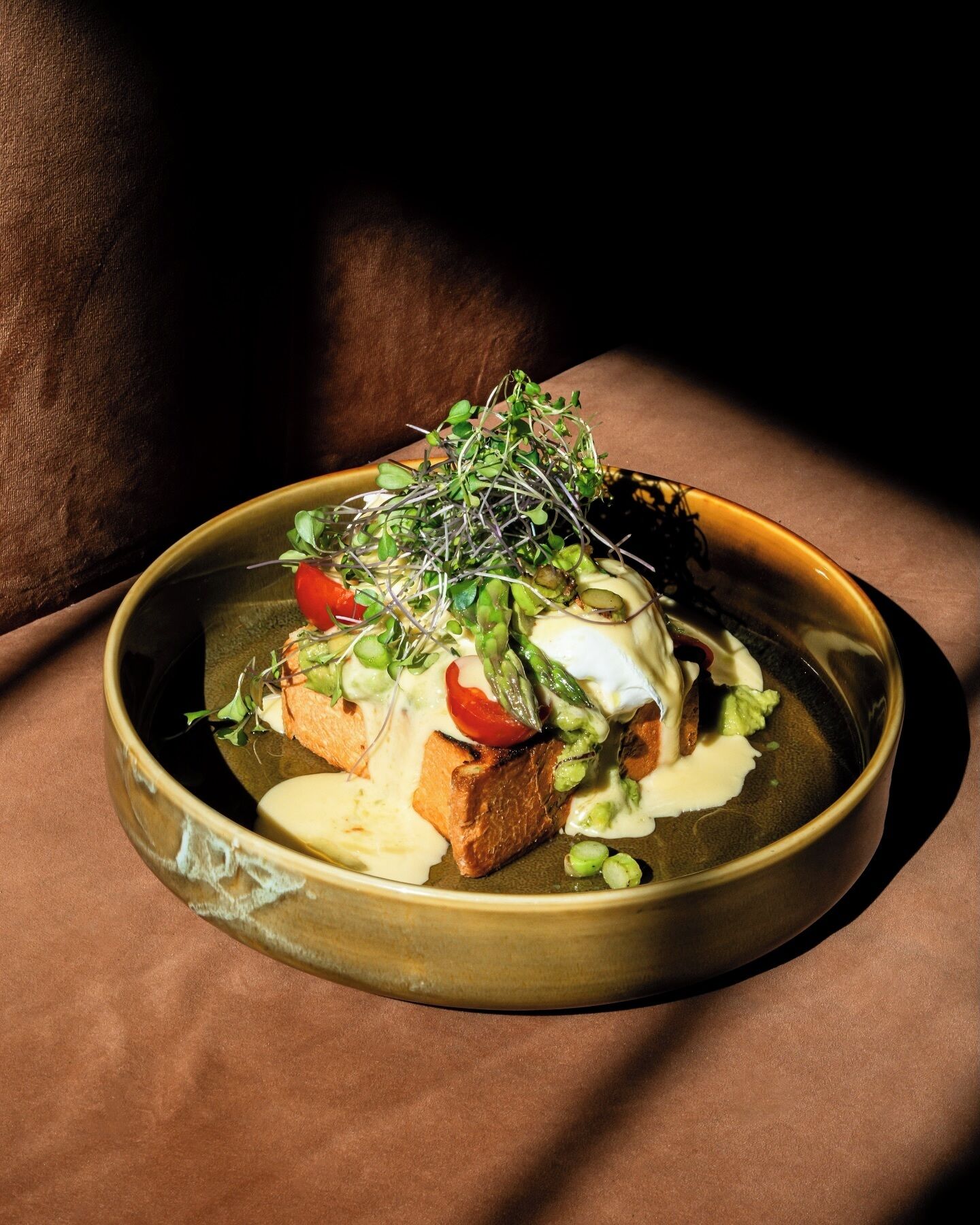 A plate of food with a variety of vegetables and a poached egg on a textured surface.