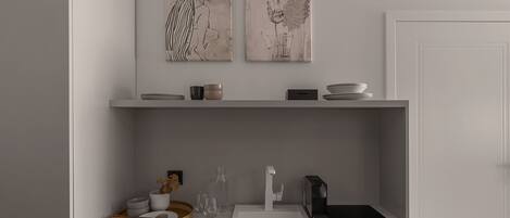 A modern kitchen with a white countertop, a built-in stove, and a sink. There are two wall-mounted shelves above the counter holding bowls and a vase.