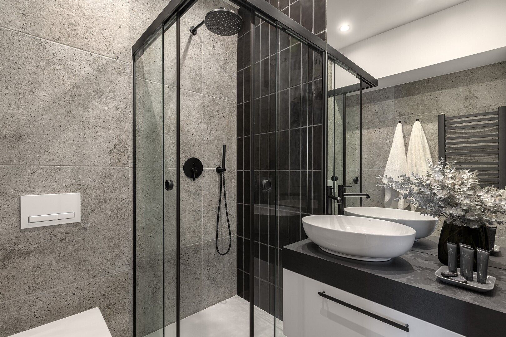 A modern bathroom with a glass-enclosed shower, a white sink, and a large mirror.