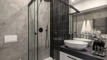 Une salle de bain moderne avec une douche à parois de verre, un lavabo blanc et un grand miroir.