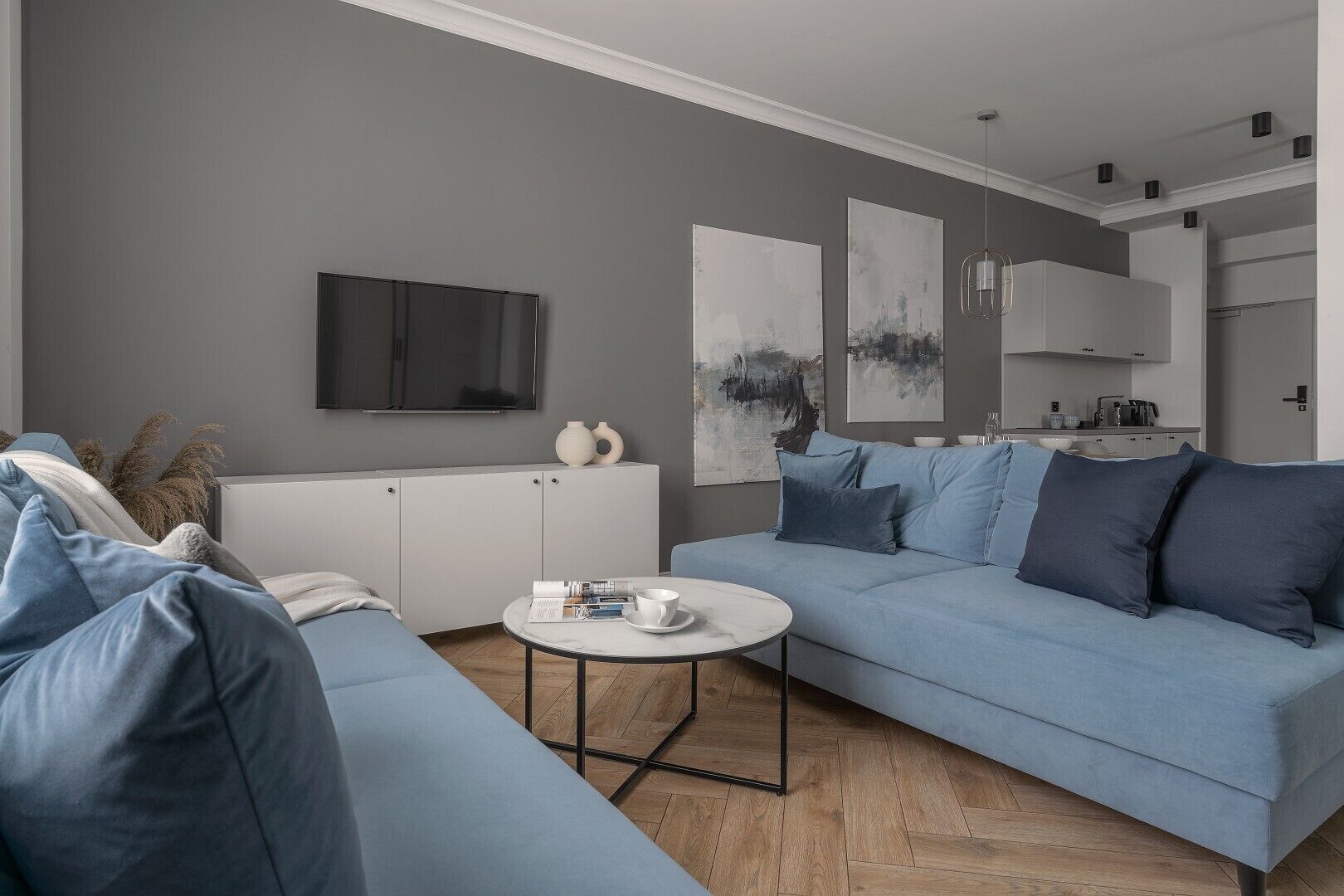 A modern living room with a grey sofa, a white coffee table, and artwork on the walls.