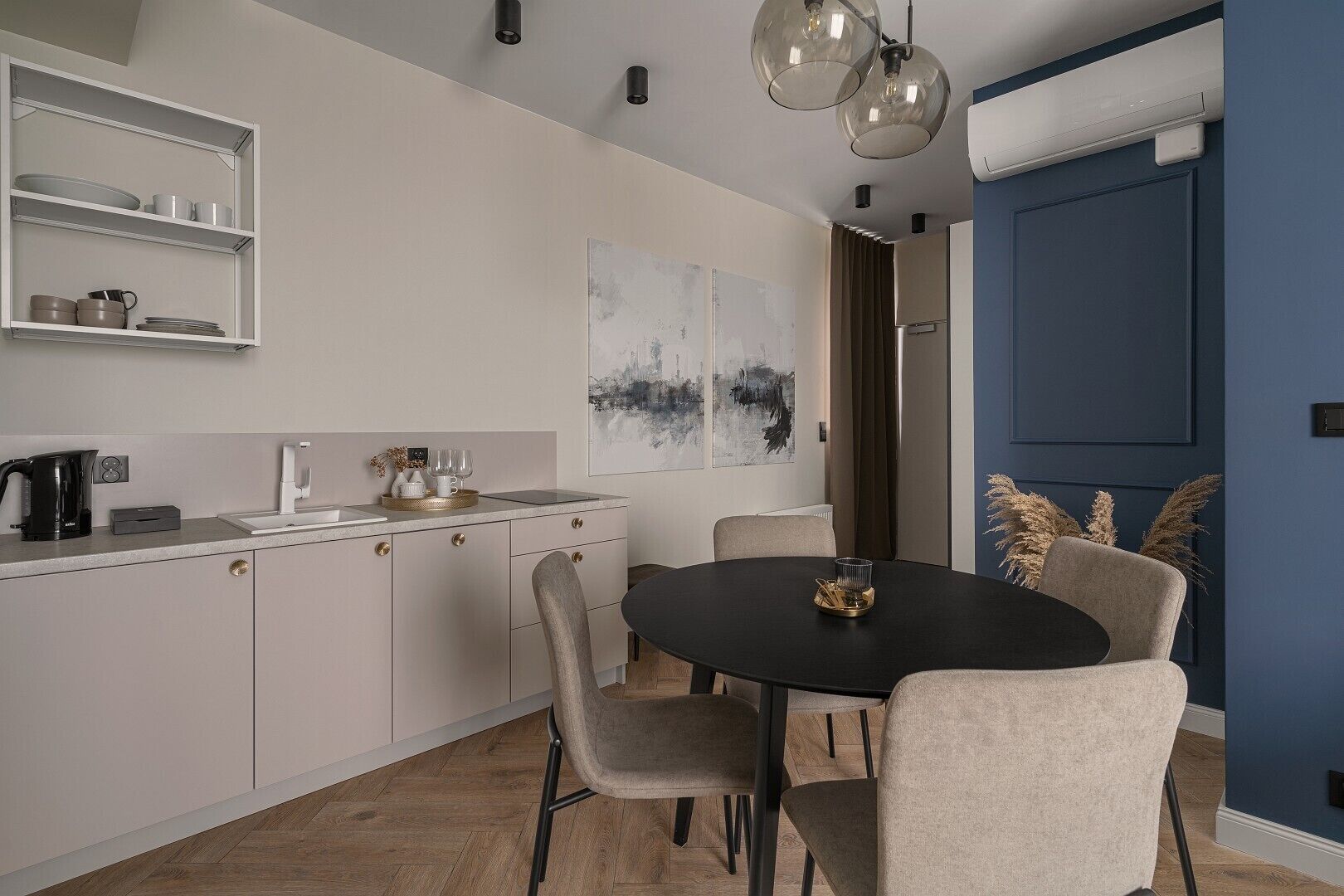 A modern kitchen with a round dining table, chairs, and a coffee machine.