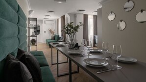 A modern dining area with a long table set for a meal, a green sofa, and a minimalist decor. - Apartio Rooms Katowice (Katowice)