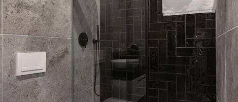 A modern bathroom with a glass-enclosed shower, a white toilet, and a tiled floor.