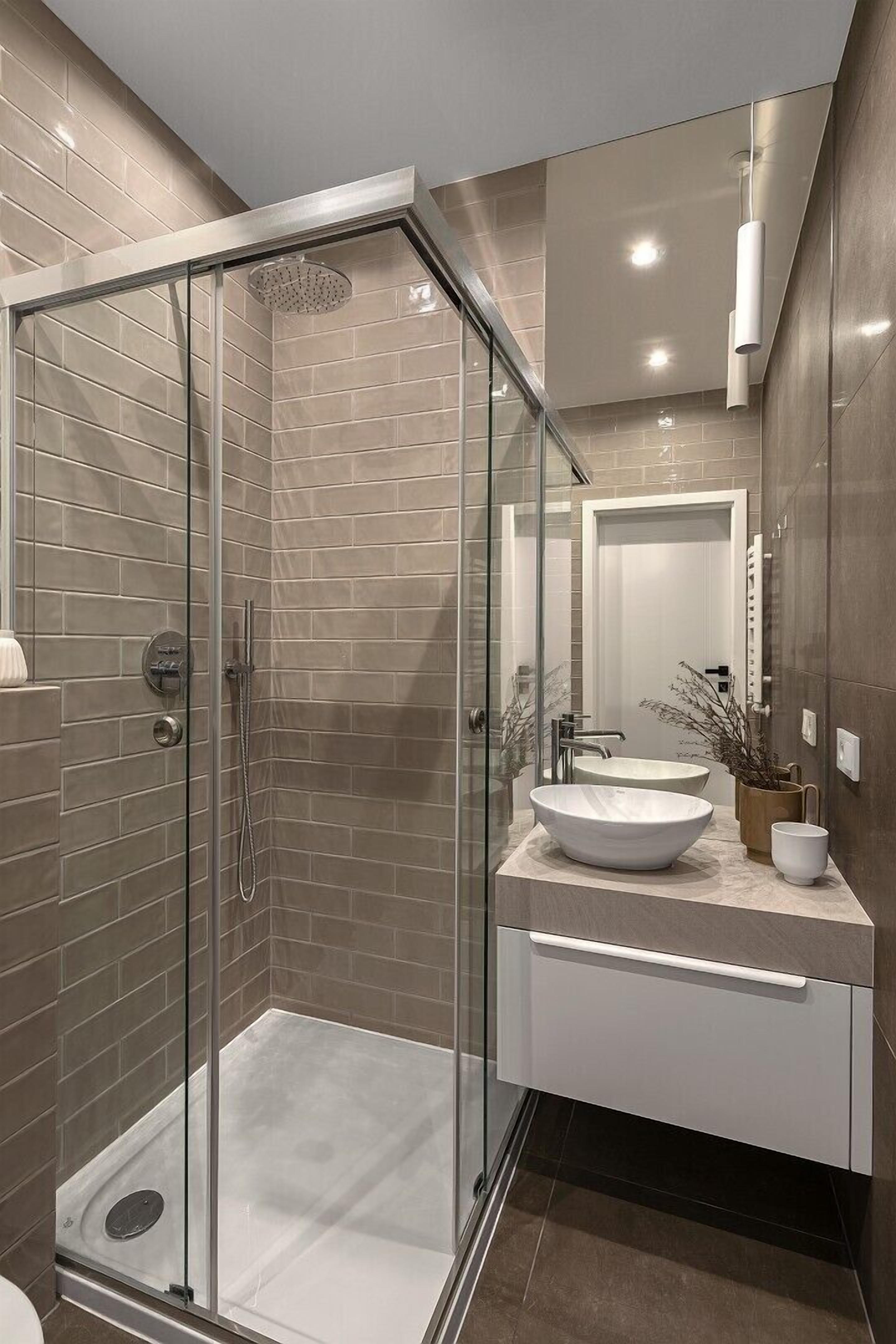 Un baño moderno con ducha de vidrio, lavabo y tocador con espejo.
