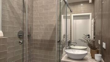 Un baño moderno con ducha de vidrio, lavabo y tocador con espejo.