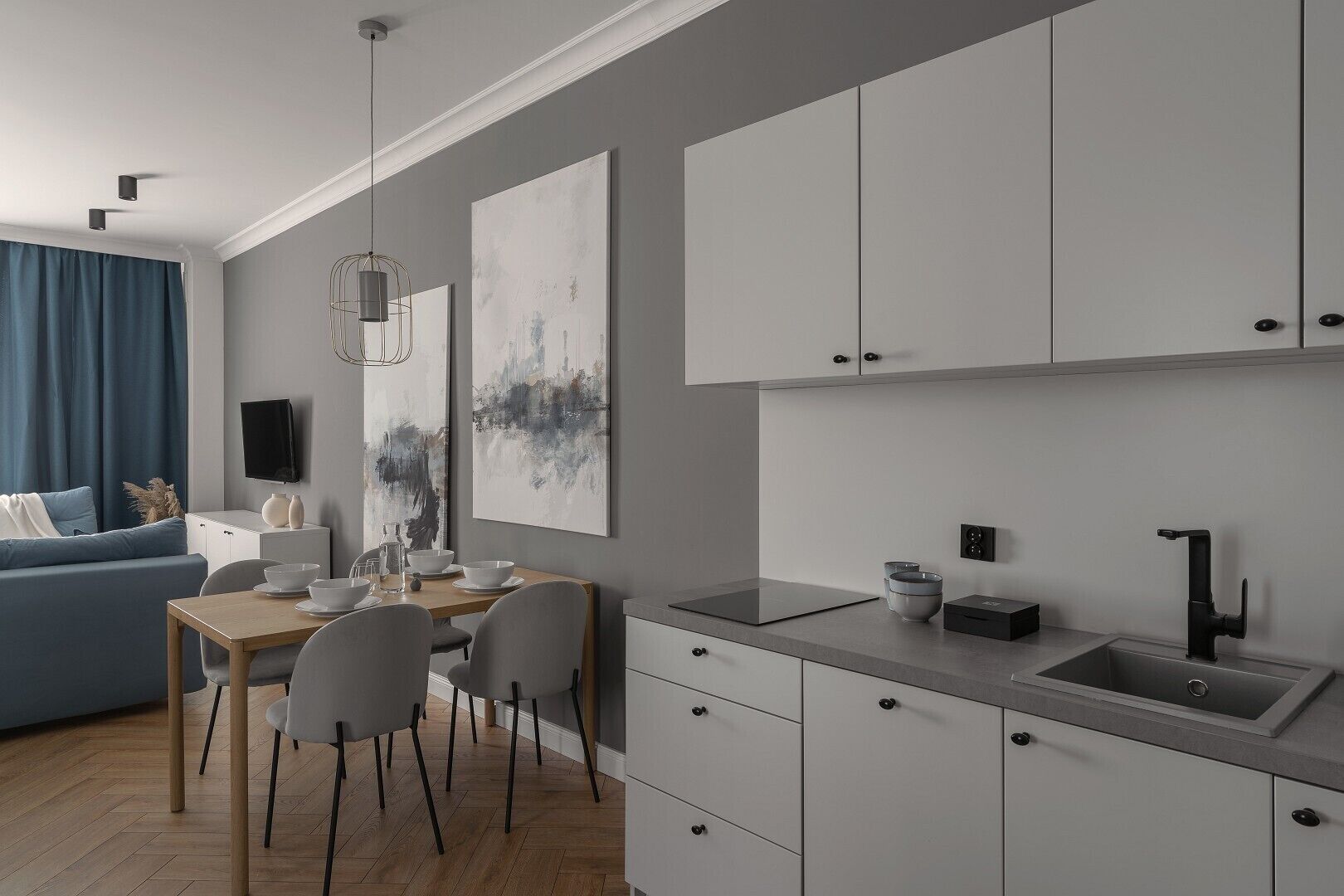 A modern kitchen with white cabinets, a grey countertop, and a black faucet.