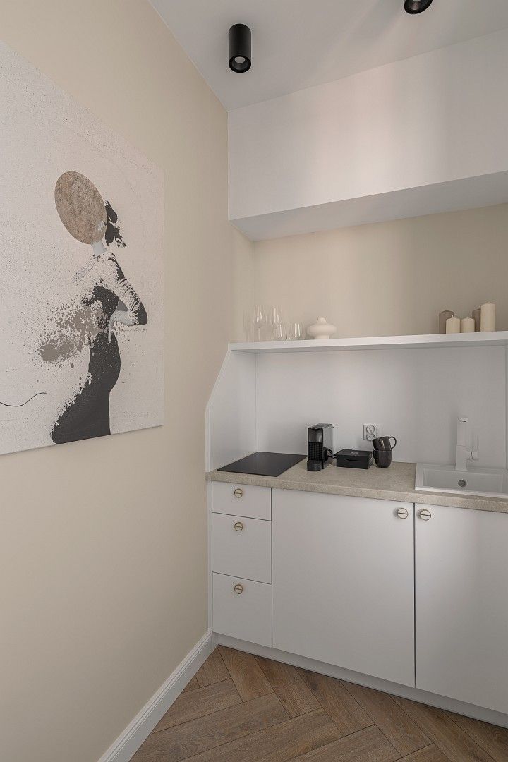 A modern kitchen with white cabinetry, a countertop with a coffee maker, and a wall-mounted light fixture.