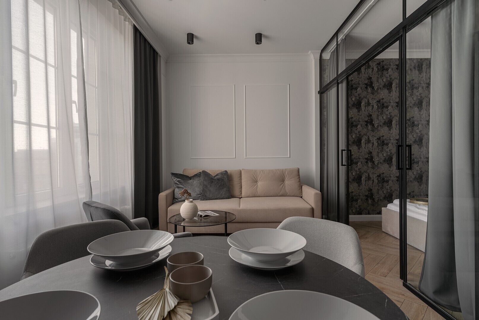 A modern living room with a sofa, a coffee table, and a dining table set with plates and bowls.