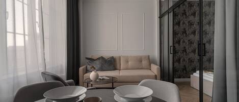 A modern living room with a sofa, a coffee table, and a dining table set with plates and bowls.