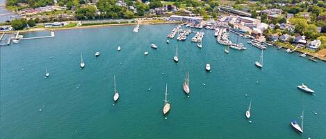 Une vue aérienne d’une marina où sont amarrés de nombreux bateaux, entourée d’une zone résidentielle et d’un paysage boisé.