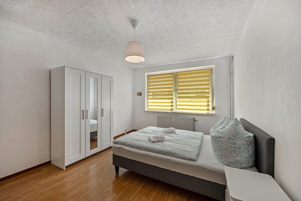 Une chambre Ă coucher comprenant un lit, une armoire, un radiateur et une fenĂŞtre avec des stores.