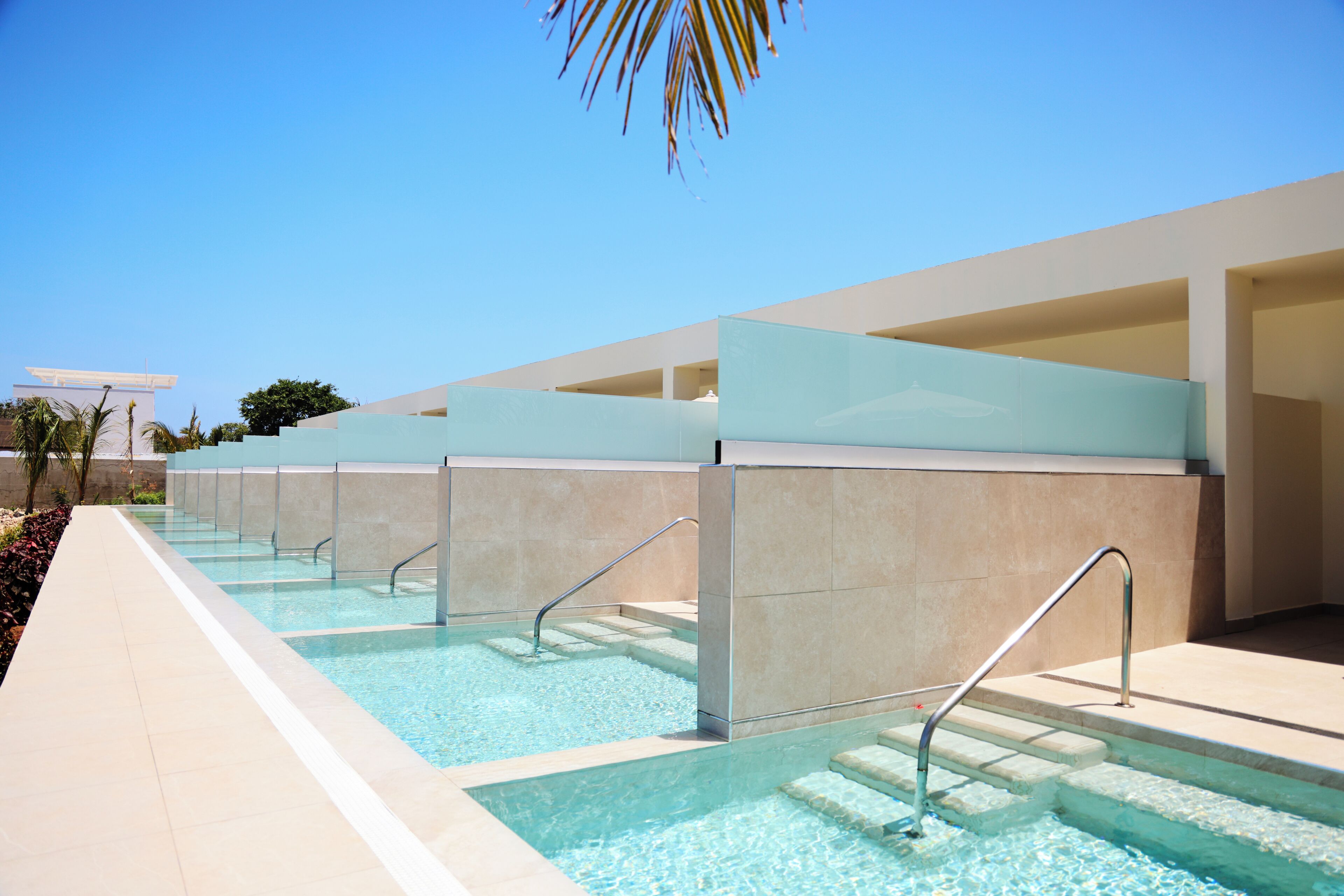 A pool area with clear water, steps leading into the pool, and a modern architectural design with glass partitions.