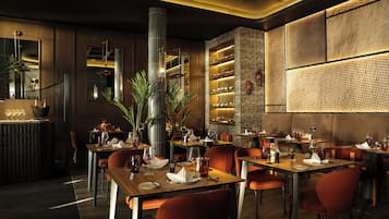 A restaurant with tables set for dining, a bar area, and a decorative wall with a textured pattern.