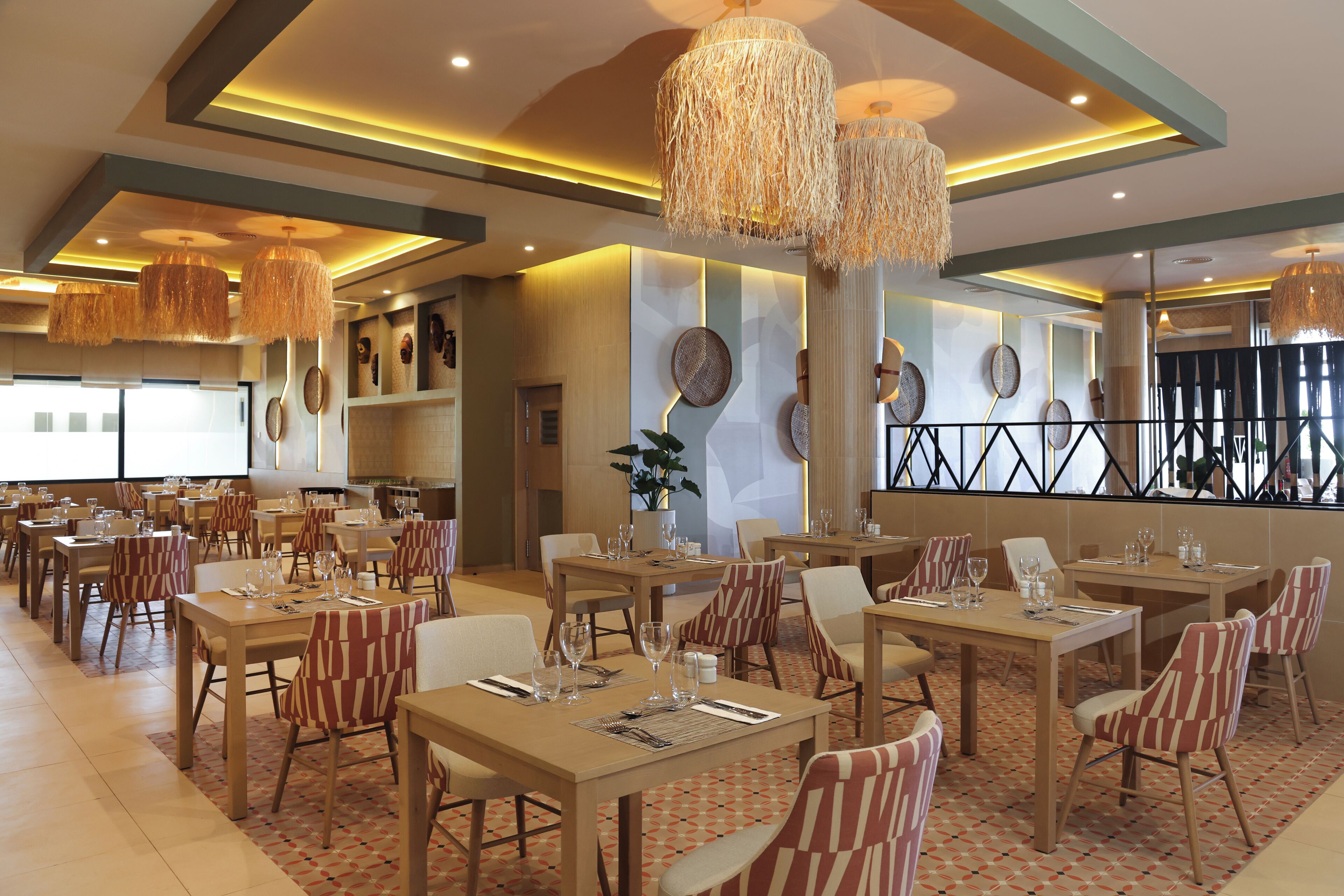 A restaurant with multiple tables and chairs, overhead lighting, and decorative wall elements.