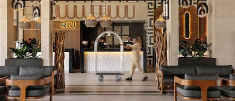 Un moderno vestíbulo de hotel con mostrador de recepción, zona de estar e iluminación distintiva.