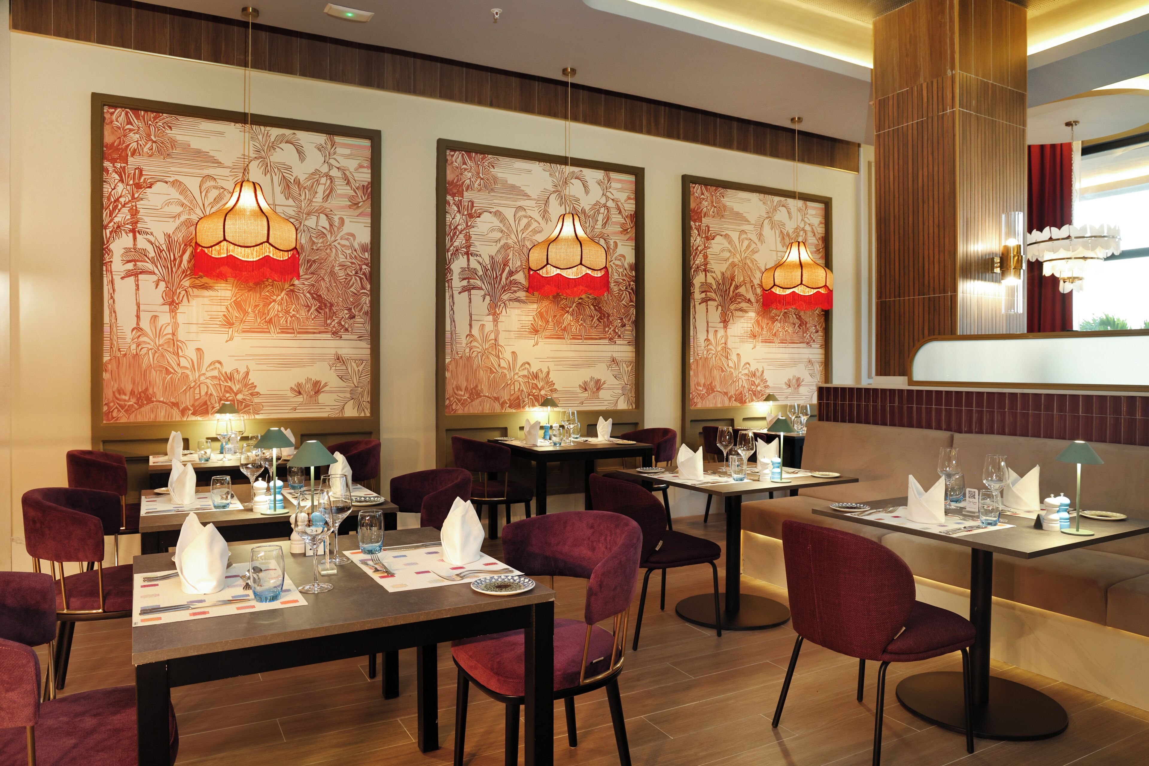 A restaurant with tables set for dining, chairs, and hanging pendant lights.