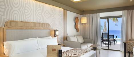 A hotel room with a bed, a sofa, a table, and a view of the ocean.