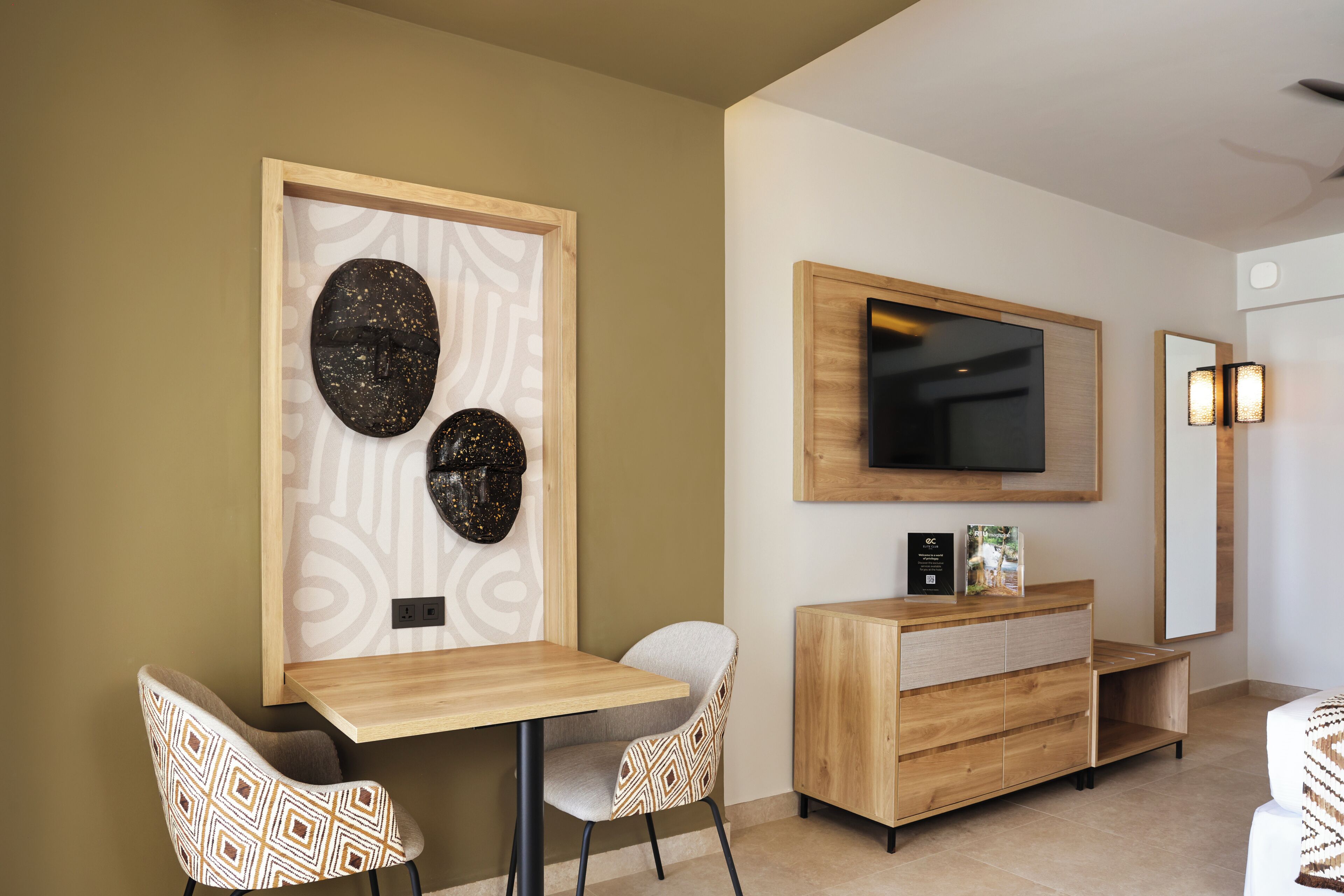 Una sala de estar moderna con un mueble bajo para televisión de madera, un televisor de pantalla plana y dos sillones estampados.