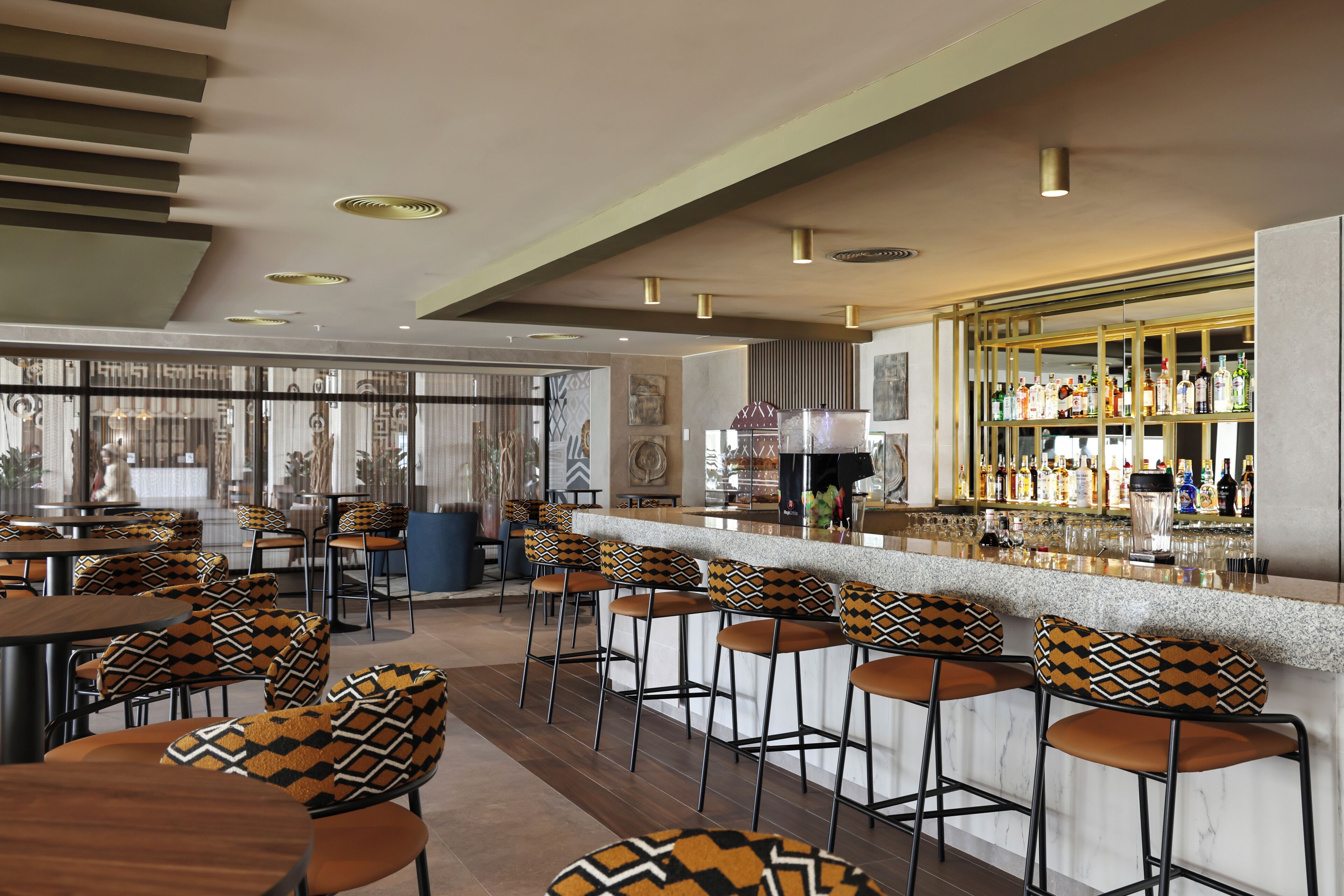 Un espace bar avec des tabourets, un comptoir et une variété de bouteilles.